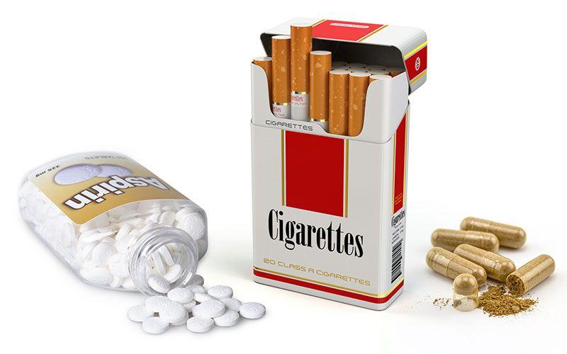 An aspirin bottle, a box of cigarettes, and an herbal supplement